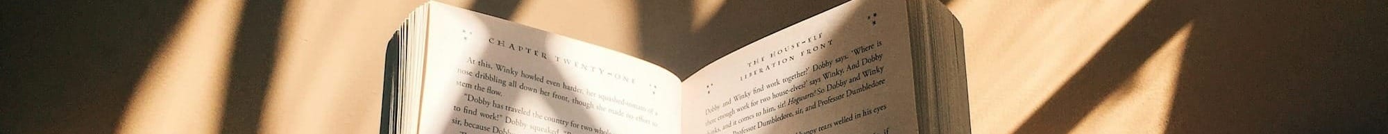 person holding book sitting on brown surface