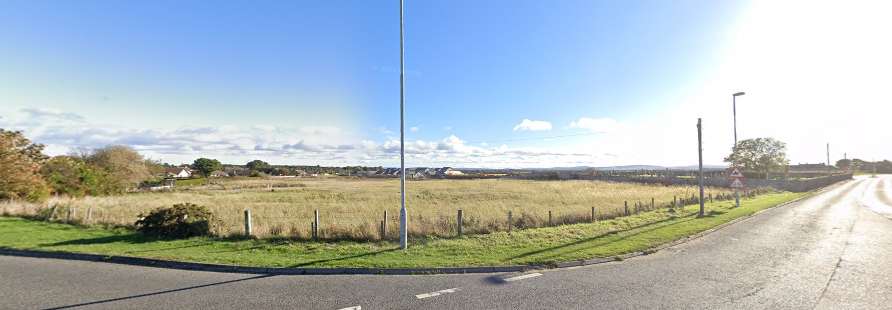 Image from Google Streetview of the site of the early medieval monastery of Kinneddar in Moray. It's a flat grassy field with a new housing estate encroaching on it from the east. 