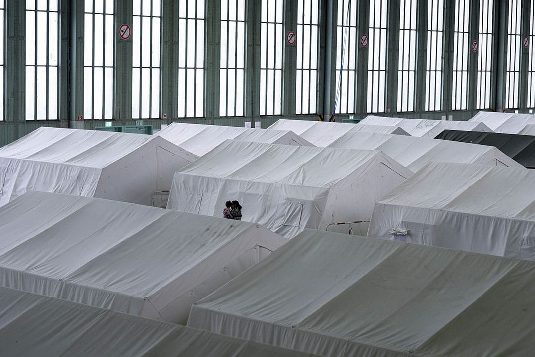 2015年12月11日,柏林, 德国政府与志愿组织合作，于废弃了的滕珀尔霍夫机场 (Templehof) 设立难民营。图为一名妇女带着子女经过帐蓬。摄：Ashley Gilbertson / VII Photo for UNICEF