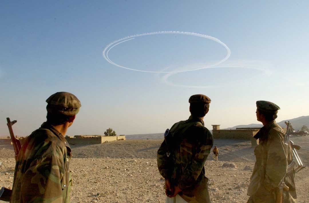 2002年9月15日，阿富汗，反塔利班士兵看著美國轟炸機在阿富汗托拉博拉地區飛過後留下的煙跡。攝：Chris Hondros/Getty