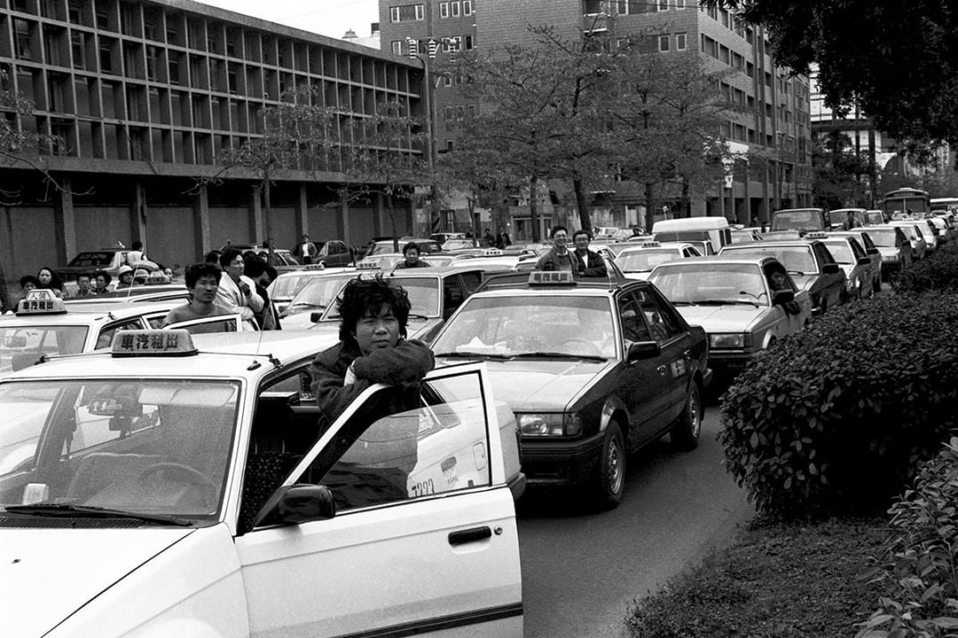 1989  80年代末台北交通黑暗期，塞车阵中的计程车司机，早年计程车没有统一颜色，後来统一改为黄色成为民众口中的小黄。