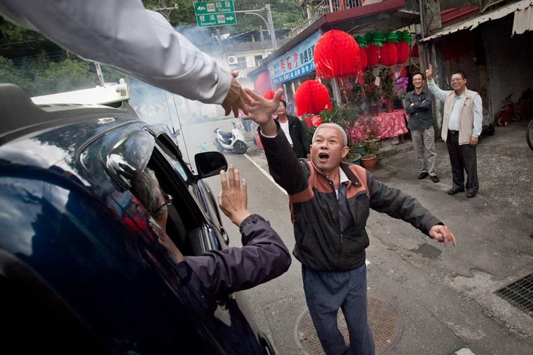  民众向车上的蔡英文握手。