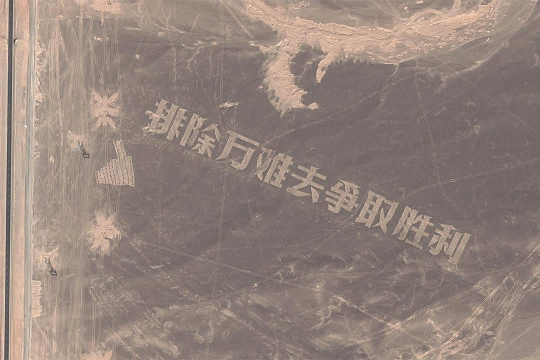 新疆哈密戈壁滩用碎石堆积成的巨大「排除万难去争取胜利」大字。