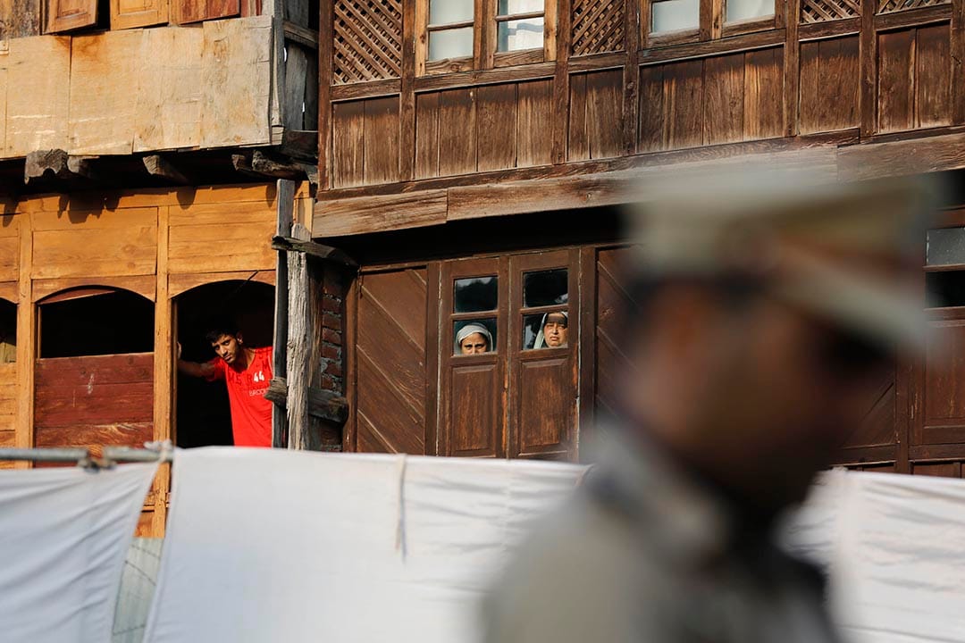 幾名喀什米爾市民看著警察祈禱。