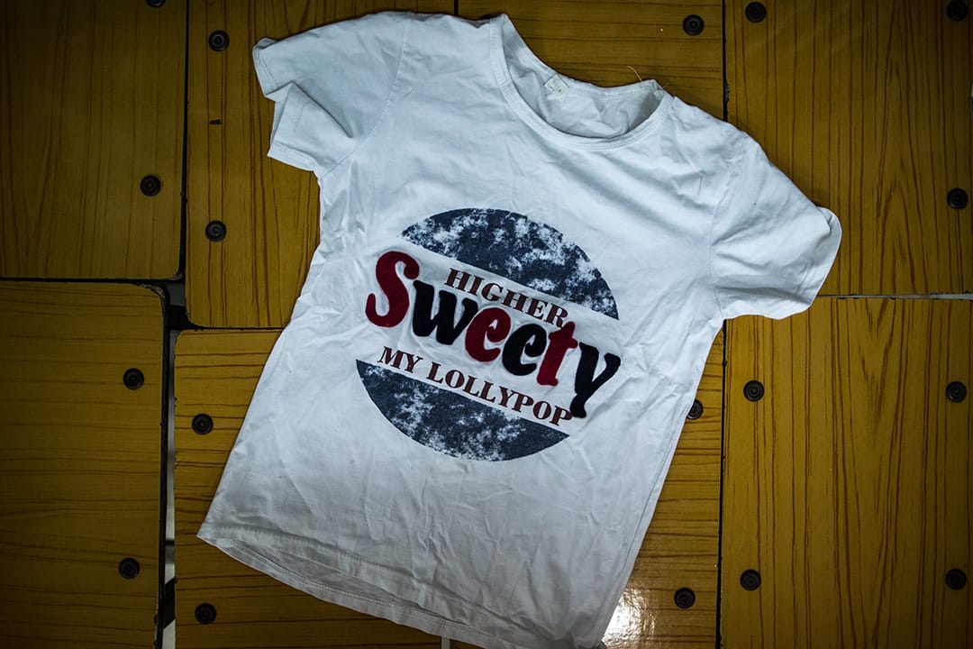 河會小學受災安置點，11歲的李仕亮在洪水來逃跑時，他幫媽媽執拾行裝，就把這件 T 恤塞了進去。這 T 恤是媽媽帶他去買時親自挑的，「我穿這件比較帥！」 他喜歡白色的衣服，「因為白色看著亮。」