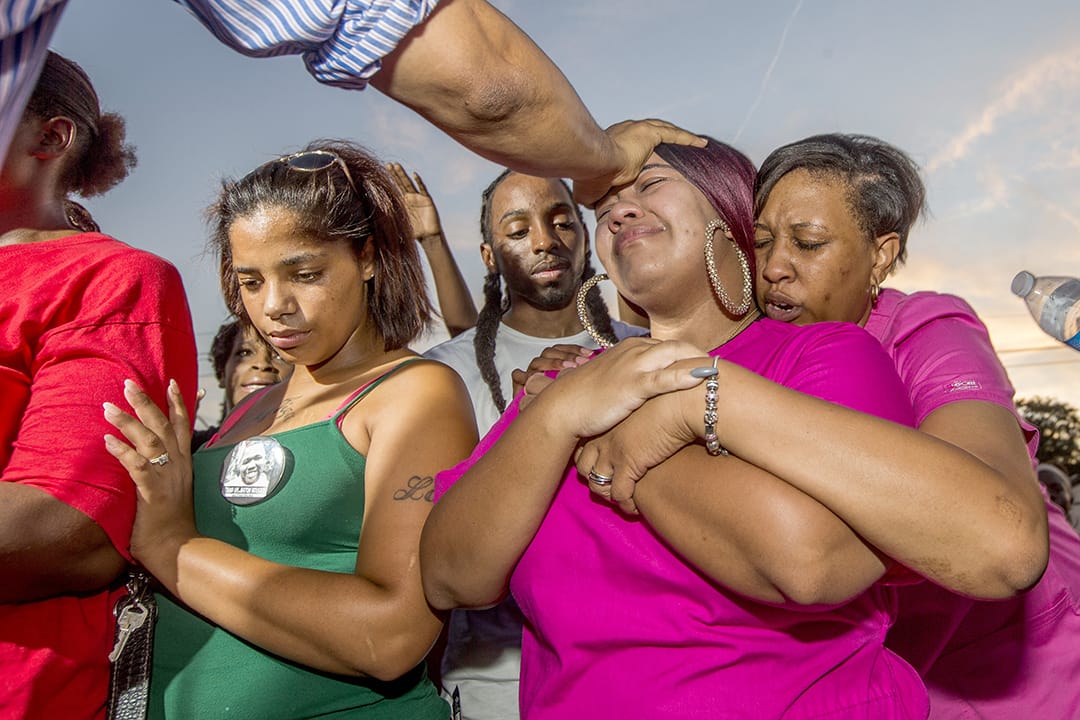 黑人小贩斯特林(Alton Sterling)的亲友在他被射杀的地方哭泣。