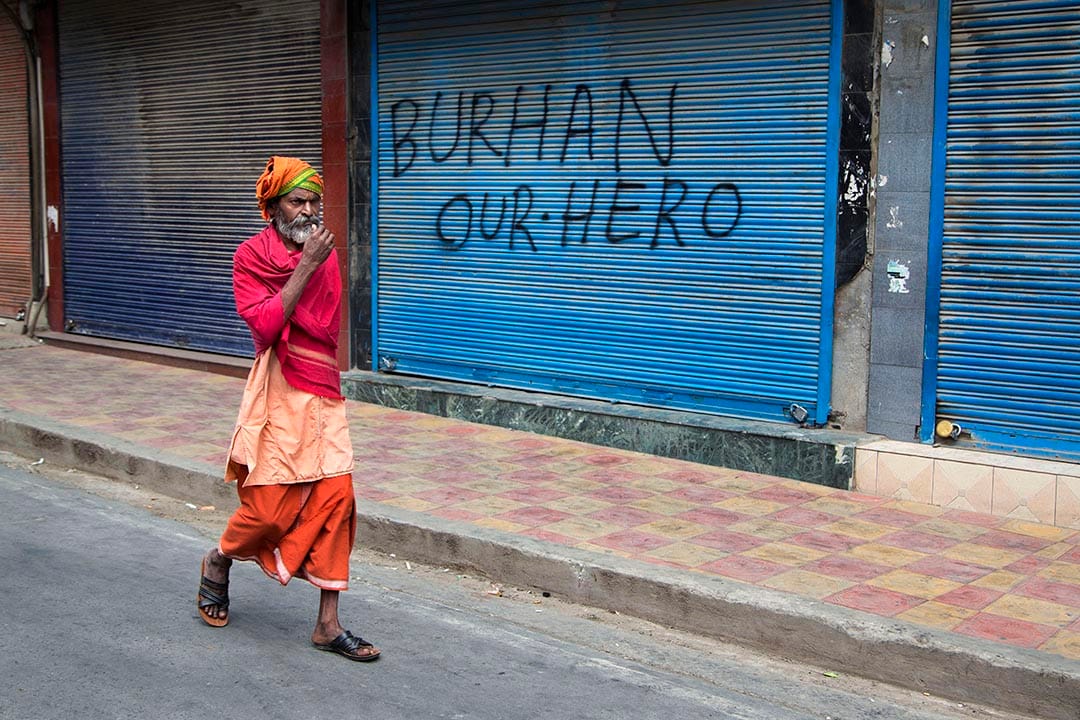 一名僧侶走過一家門外噴有支持Burhan Wani口號的店鋪。