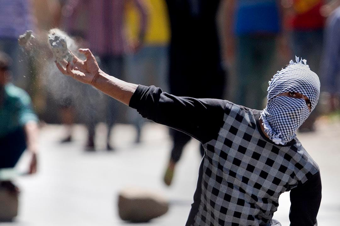 一名蒙面的喀什米爾示威者向警方投擲石頭。 