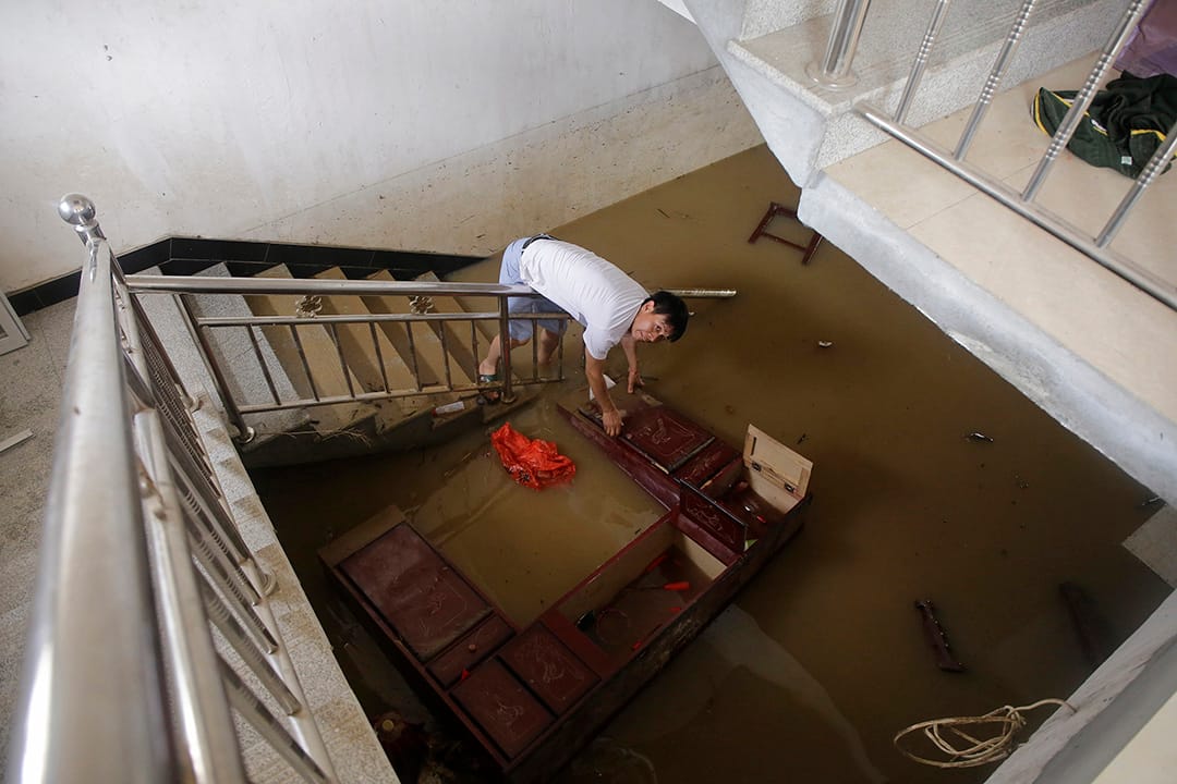  中國武漢，河水缺堤，一名村民在家中搜索被淹沒的財物。