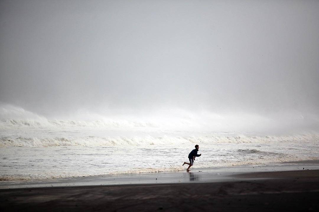 紐約，一個小孩在颱風來臨前的沙灘上逐浪。