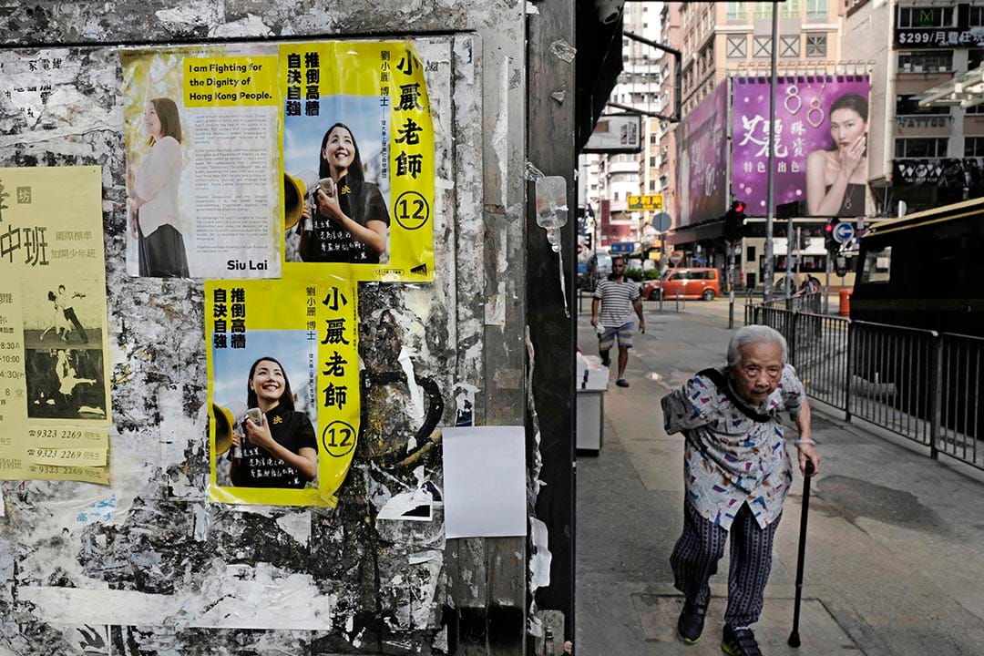 一名老人走过张贴着小丽民主教室宣传单张的街道。