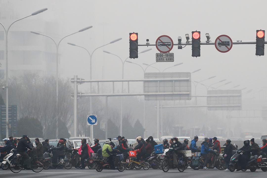 中國北京，市民騎單車和電動車橫過馬路。 