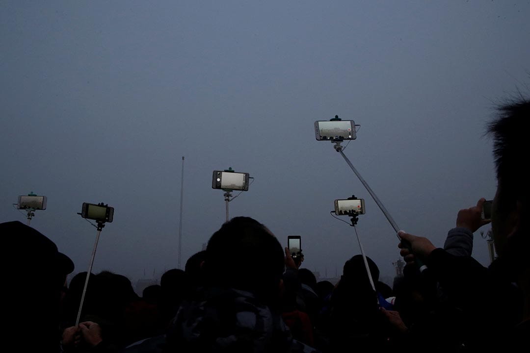 中國北京，市民在霧霾中為天安門廣場的升𣄃儀式拍照留念。