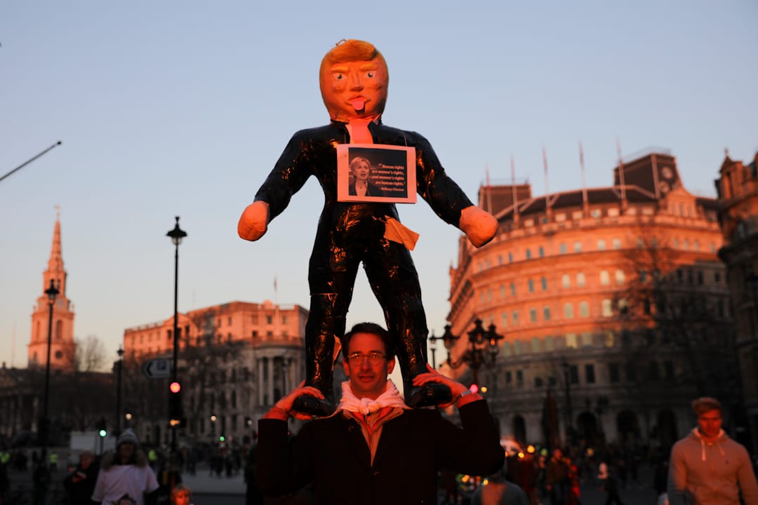 在英國倫敦，一名抗議者手持特朗普總統肖像在街上遊走。