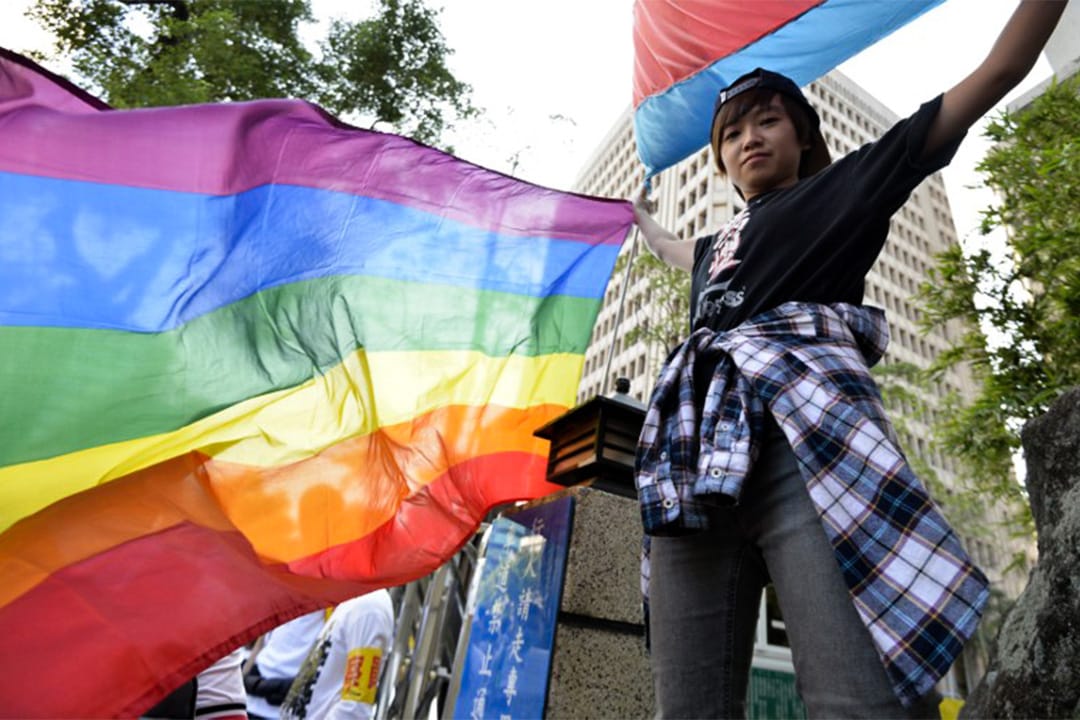 有台湾青年高举象征性少数群体(LGBT)的彩虹旗帜。