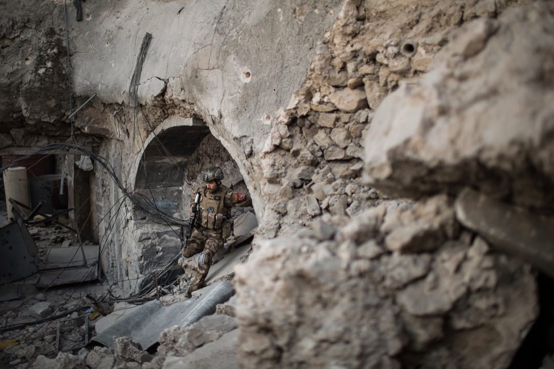 2017年7月5日,一名伊拉克政府軍成員正穿越已成為頹垣敗瓦的摩蘇爾舊城區。