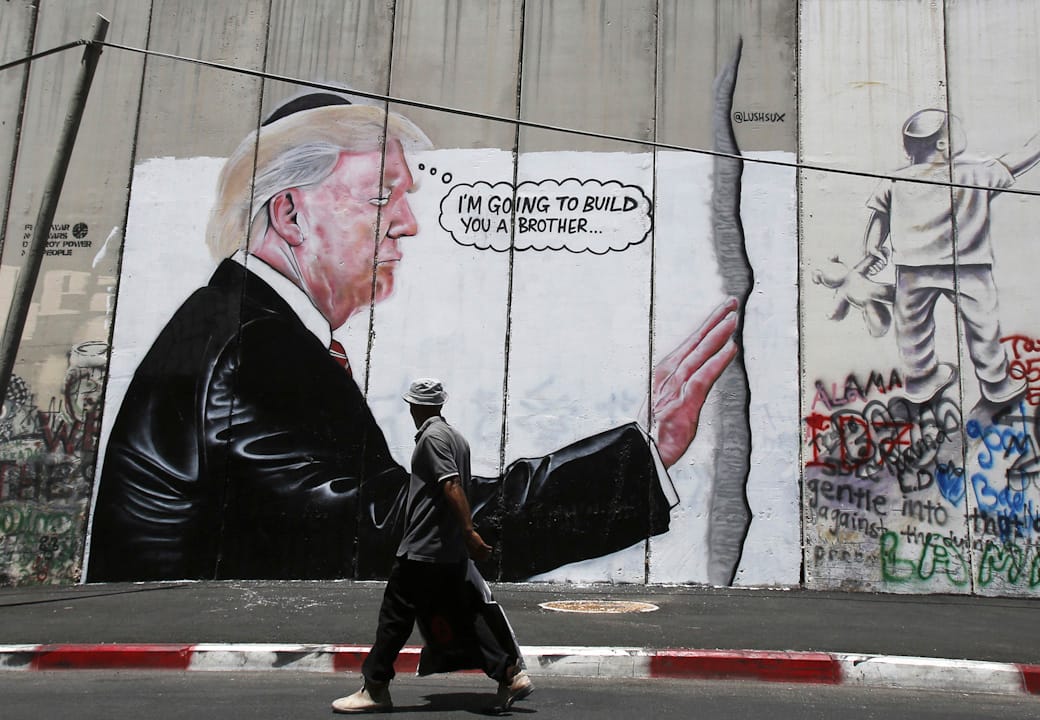 2017年8月4日，在巴勒斯坦的伯利恆，一名途人行經一幅畫了特朗普在以巴邊境的隔離牆的情況，諷刺特朗普的墨西哥圍牆政策。
