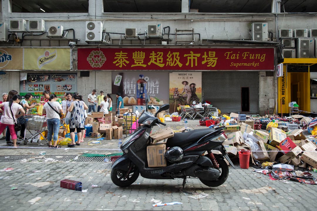 超市因断水电不能开门，市民要到超市门外户外买必需品。