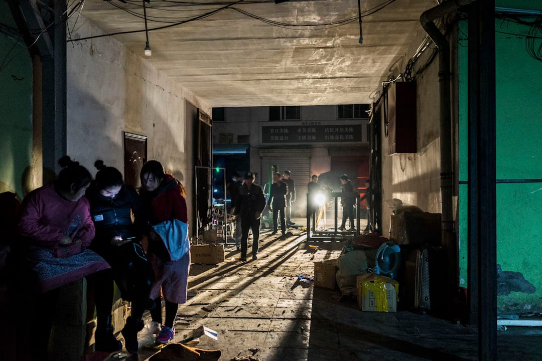 2017年11月25日晚上，一家三十人左右的服裝廠將搬遷到河北廊坊附近，男工正在將設備運上卡車，女工在旁邊看手機，等待他們把東西運上完成。