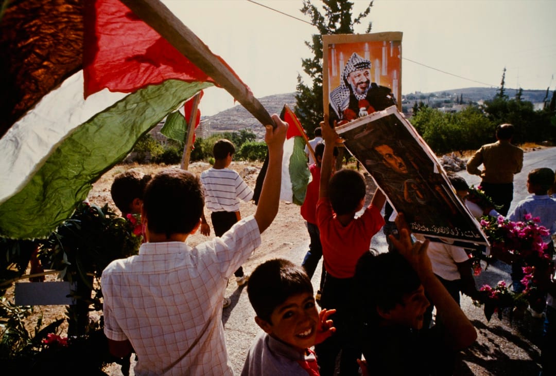 1989年6月，在巴勒斯坦被占的土地上，巴勒斯坦儿童举标语和旗帜表示支持巴解组织领导人阿拉法特。