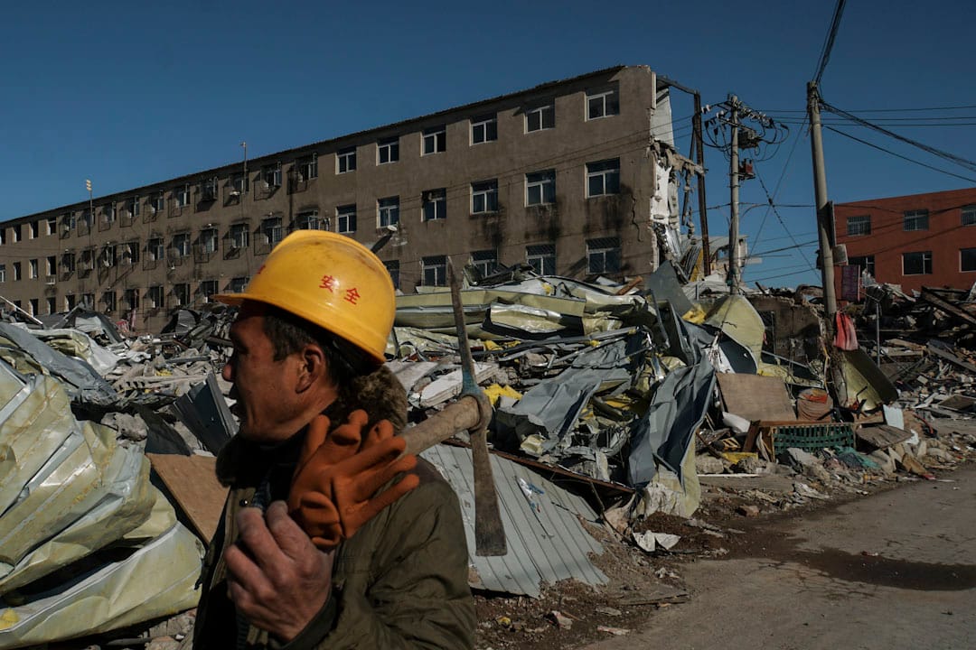 拆遷工人拿著鋤頭在廢墟中走過。