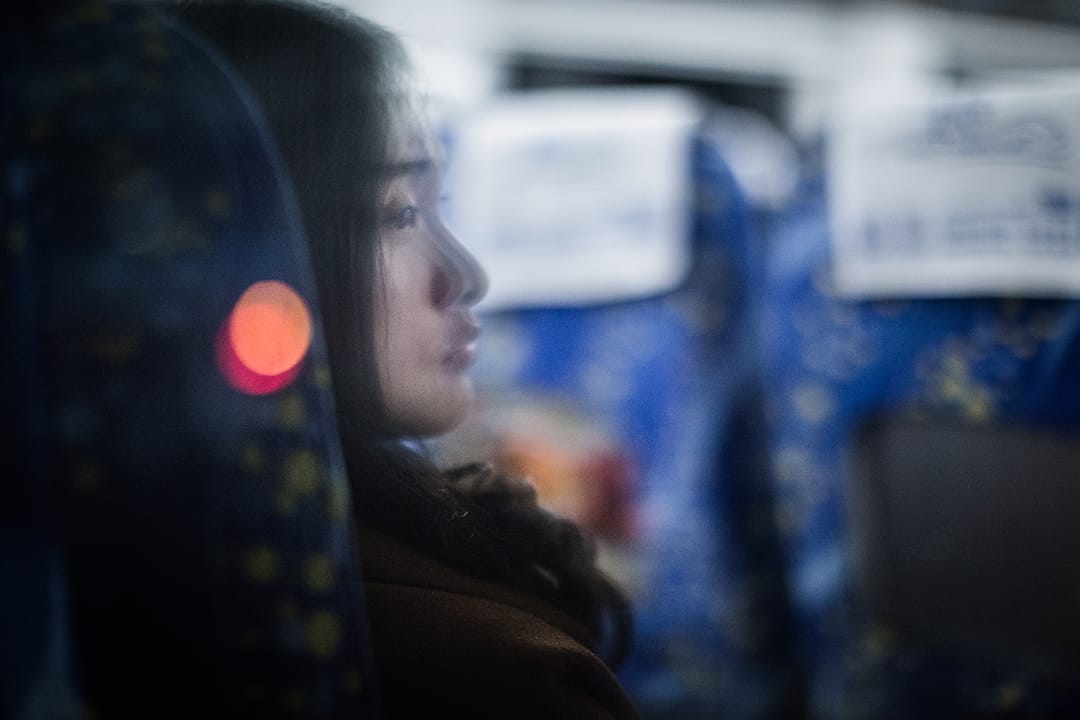 一名女子正望向車窗外,那發出微弱燈光的地方。