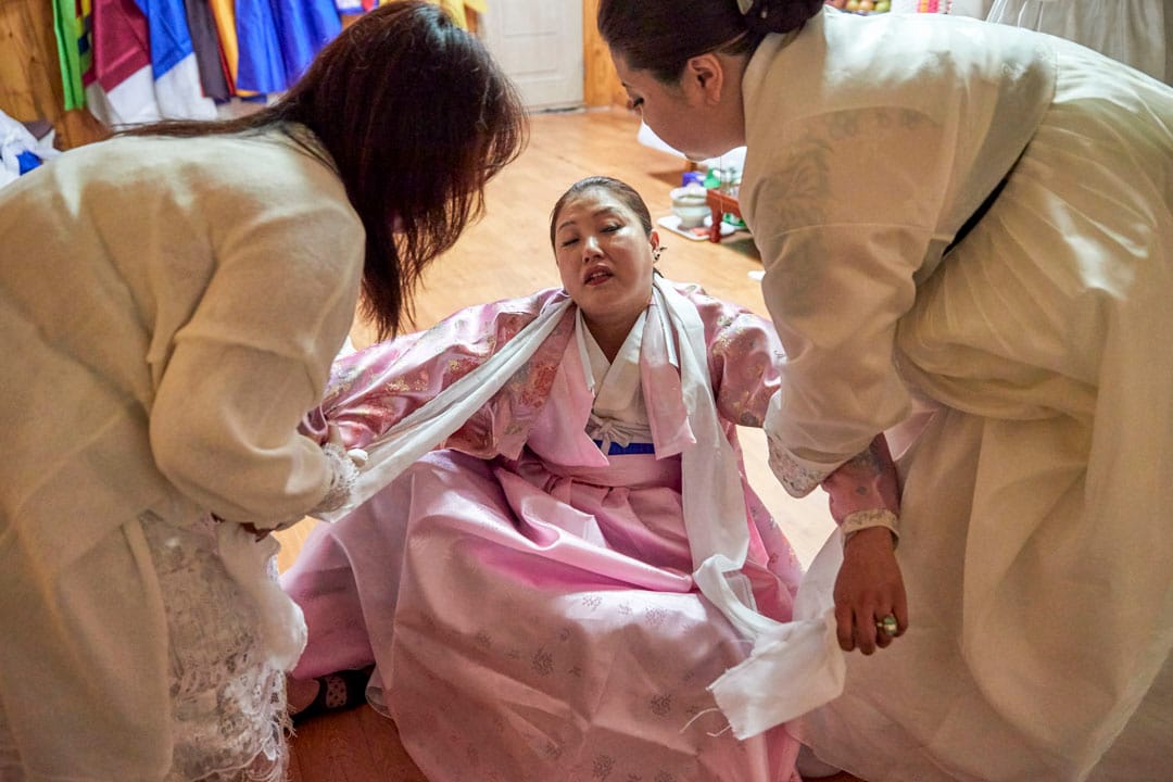 韩国京畿道，几位萨满巫师正在为一名信徒死去的母亲作名为“羊肠”的法事，其用途在于洗涤死者的灵魂和引导死者到来世。教徒相信死者的灵魂能透过巫师的身体在此法事跟信徒对话。