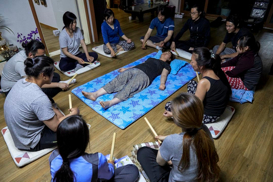 韩国堤川市，萨满巫师Cheonsindangju正和弟子们为一名女子在她的住所驱魔。