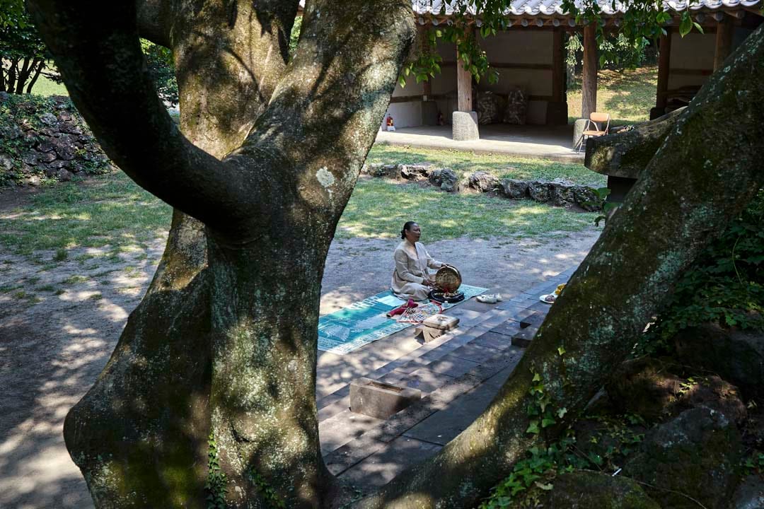 韩国济州岛，萨满巫师Dowannyeo在神树下席地祷告。