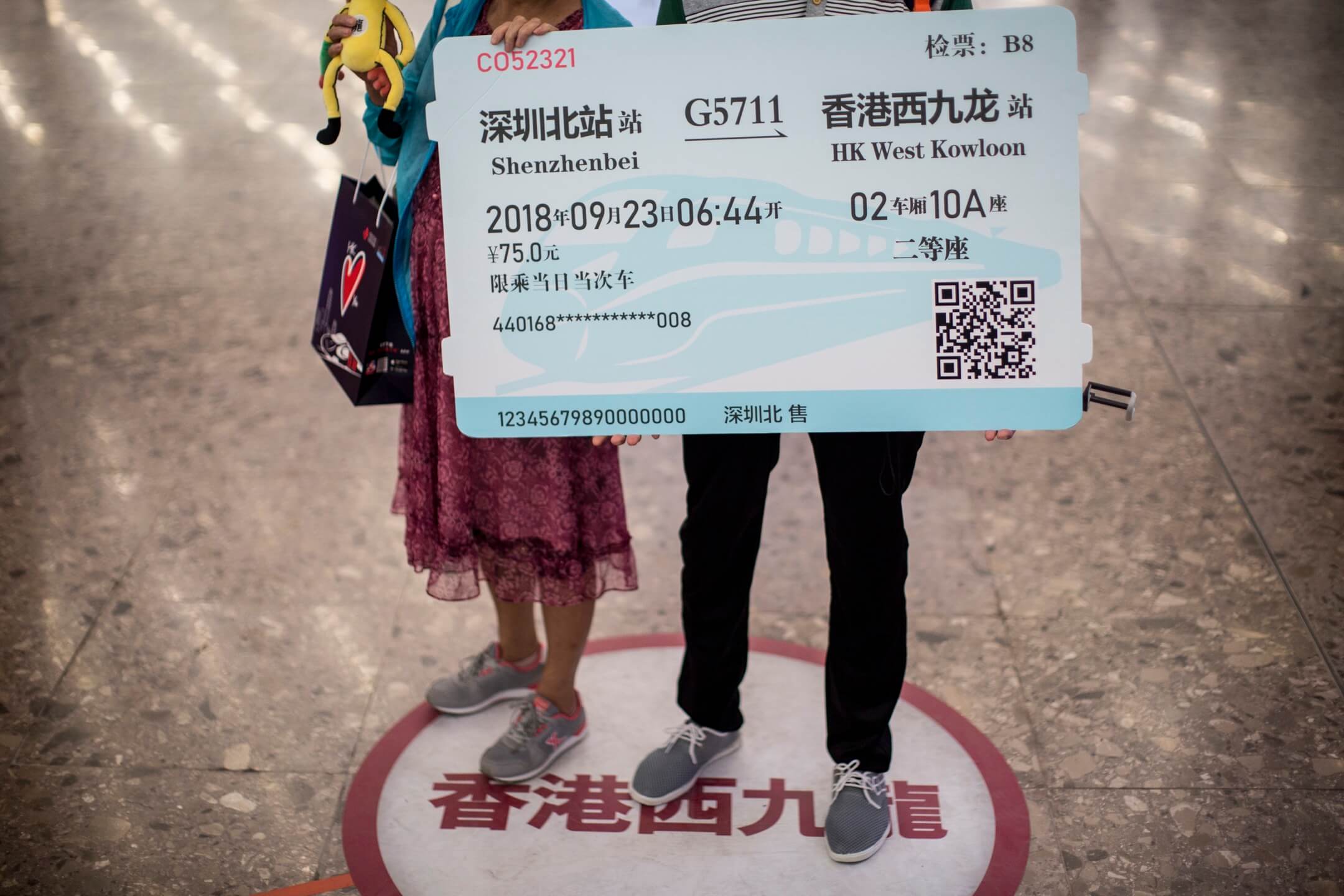香港西九龍高鐵站入境大堂,兩名內地旅客拿著道具車票拍照。