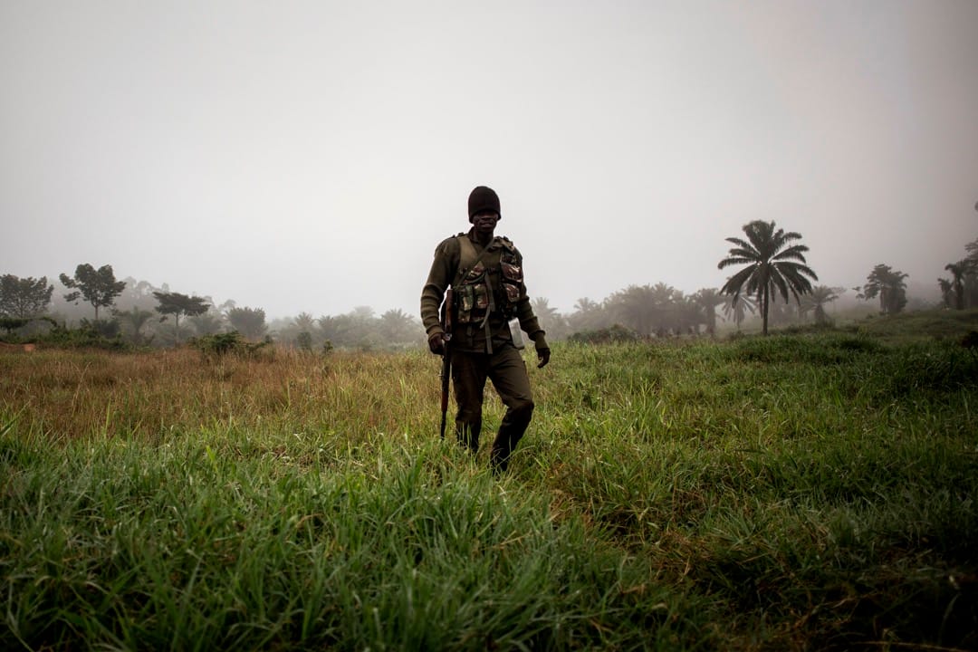 一名政府军士兵在通宵看守哨站后于清晨时分步行回到基地。