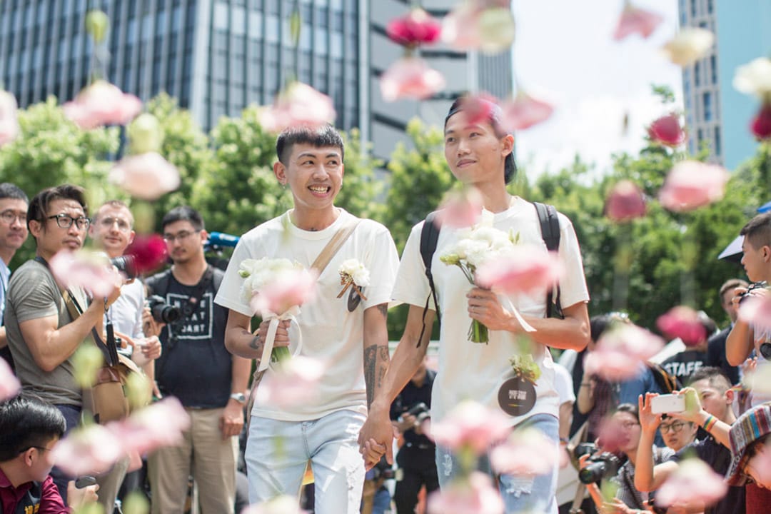 完成結婚登記的同志伴侶穿越幸福拱門踏上彩虹地毯，接受祝賀。