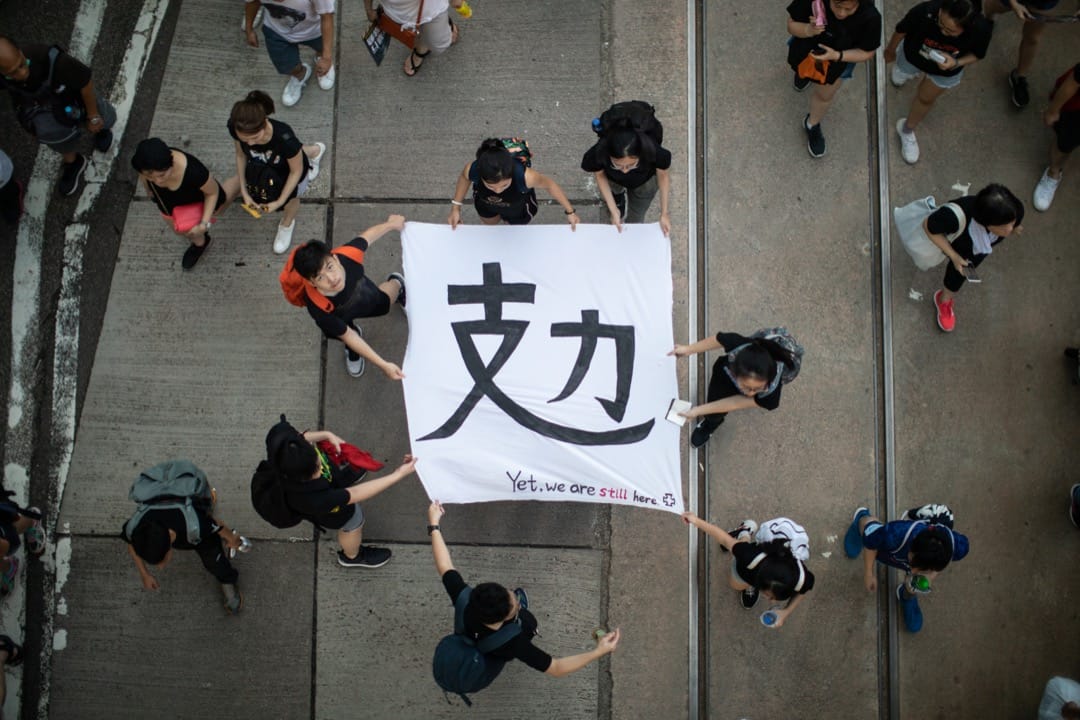 2019年7月1日，民阵发起七一大游行，有参加者拿著写有“攰”字的横幅。