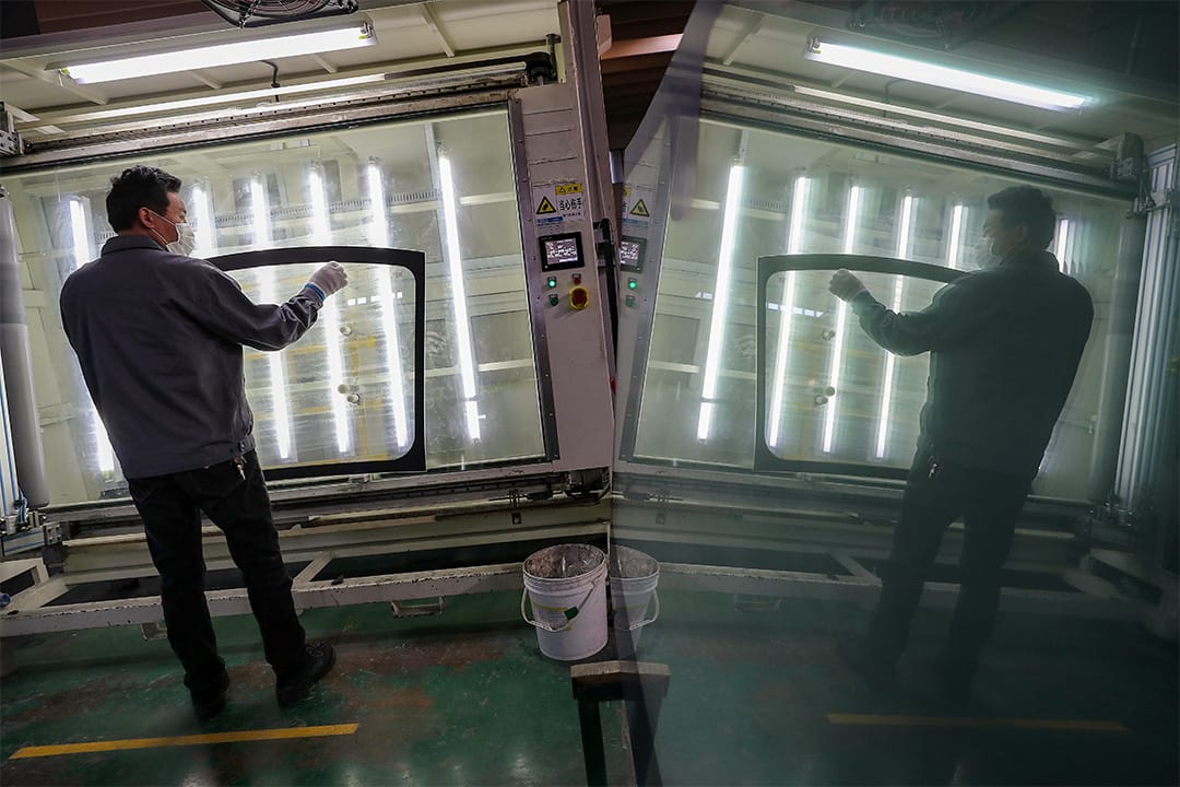 2020年3月4日南通，一名戴口罩的工人在汽車擋風玻璃廠內工作。