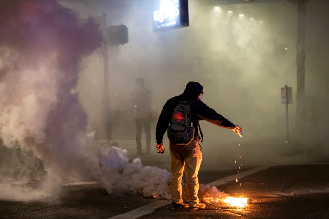 2020年7月29日，波特兰一场抗议中，一名医疗志愿队人员在催泪弹上倒水。