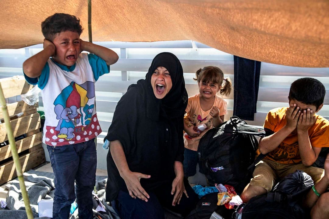 2020年9月12日，希臘萊斯沃斯島，逃離莫里亞難民營火災的難民與當地警方對峙，一名女子與孩子們在旁痛哭。