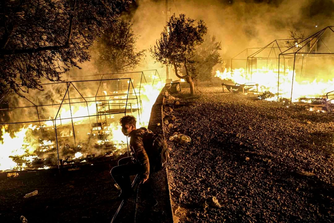 2020年9月9日，希臘萊斯沃斯島、莫里亞難民營發生火災，一名逃到希臘尋求庇護者坐看著營地被燒毀。