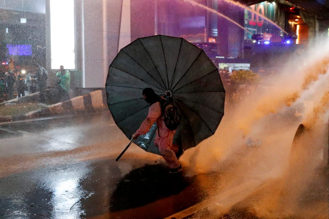 2020年10月16日泰國曼谷，一場反政府抗議活動中一名男子躲在傘下。