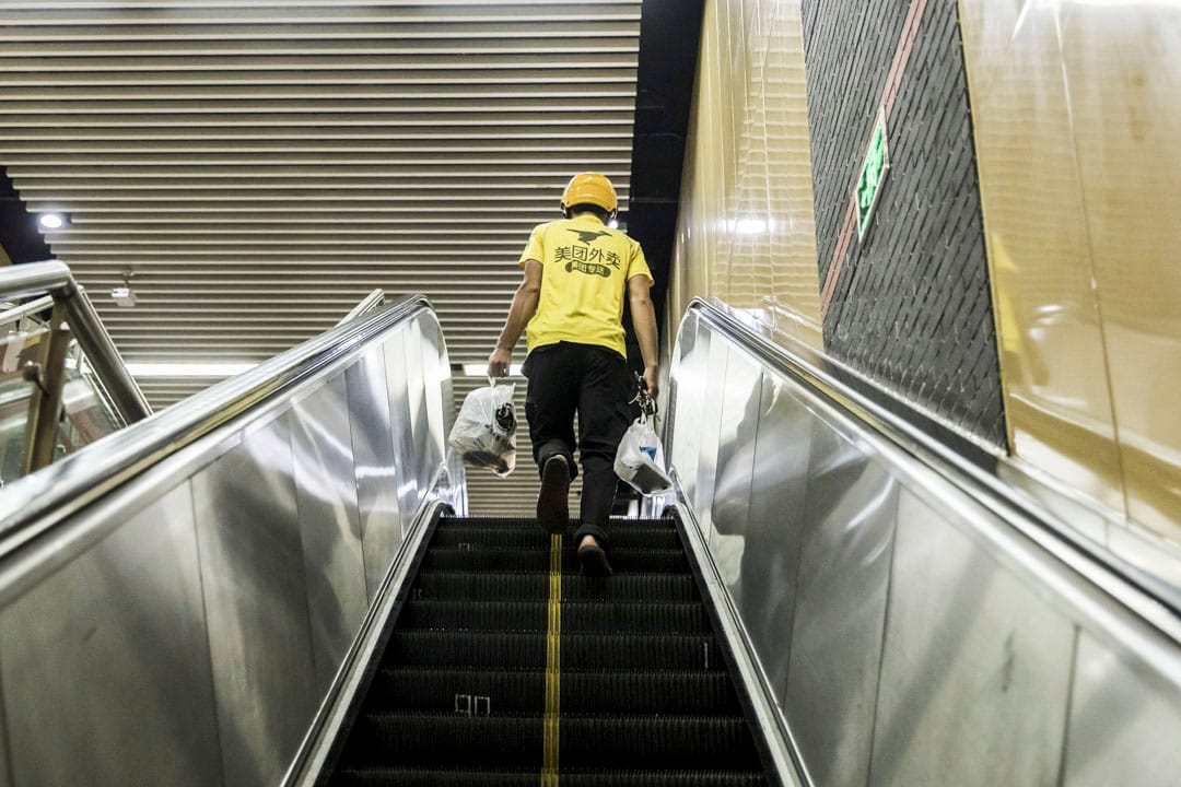 2019年8月17日,上海美團快遞員乘坐自動扶梯送食物。