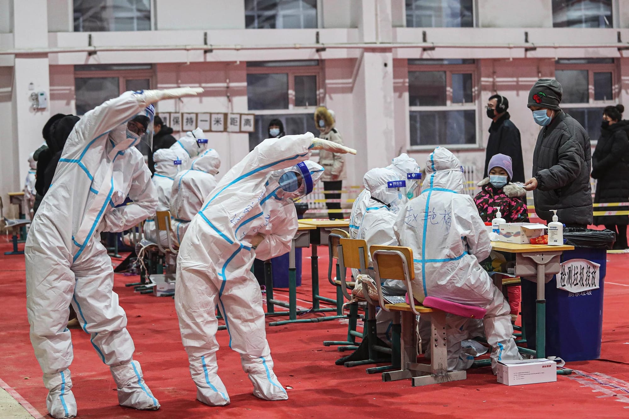 2021年1月5日中國瀋陽市,身穿防護衣的醫務人員在一個臨時檢測中心做伸展運動。