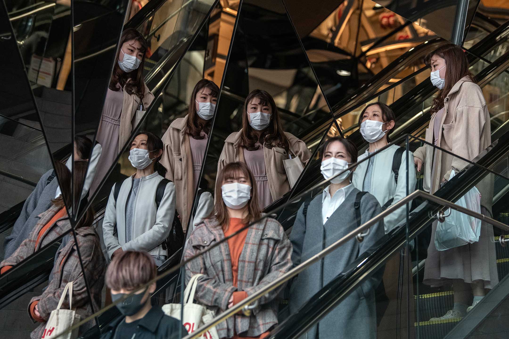 2020年4月3日日本东京,戴着口罩的人们从自动扶梯下楼。