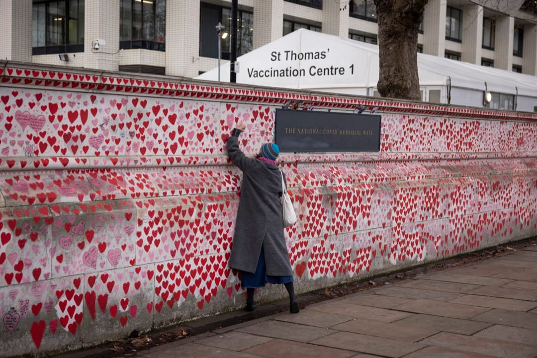 2022年1月7日，英國首都倫敦，一名市民在泰晤士河畔、專門處理2019冠狀病毒患者的聖托馬斯醫院旁邊的2019冠狀病毒悼念牆寫上悼念字句。