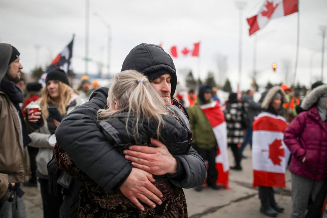 2022年2月10日，加拿大安大略省溫莎市，「自由車隊」反疫苗示威參與者堵塞通往美國的大使橋，兩名示威者在擁抱。