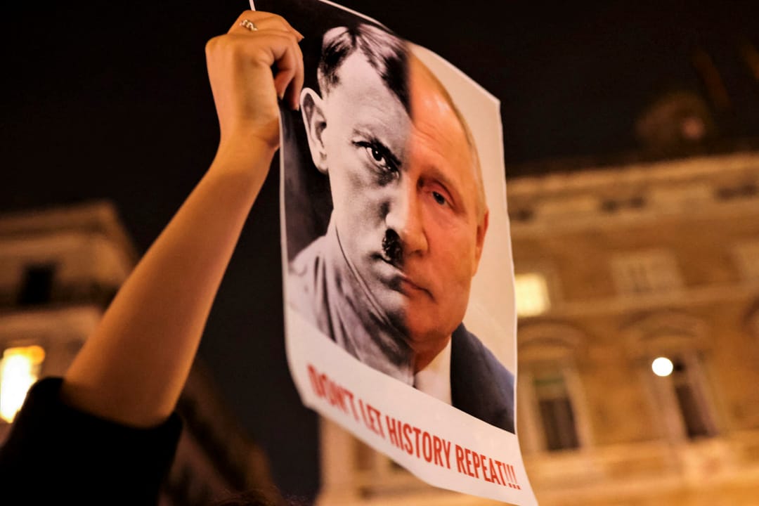 2022年2月24日，西班牙巴塞罗那，俄罗斯总统普京对乌克兰进行大规模军事行动，一名示威者举著横幅，上面印有普京和希特勒的肖像。
