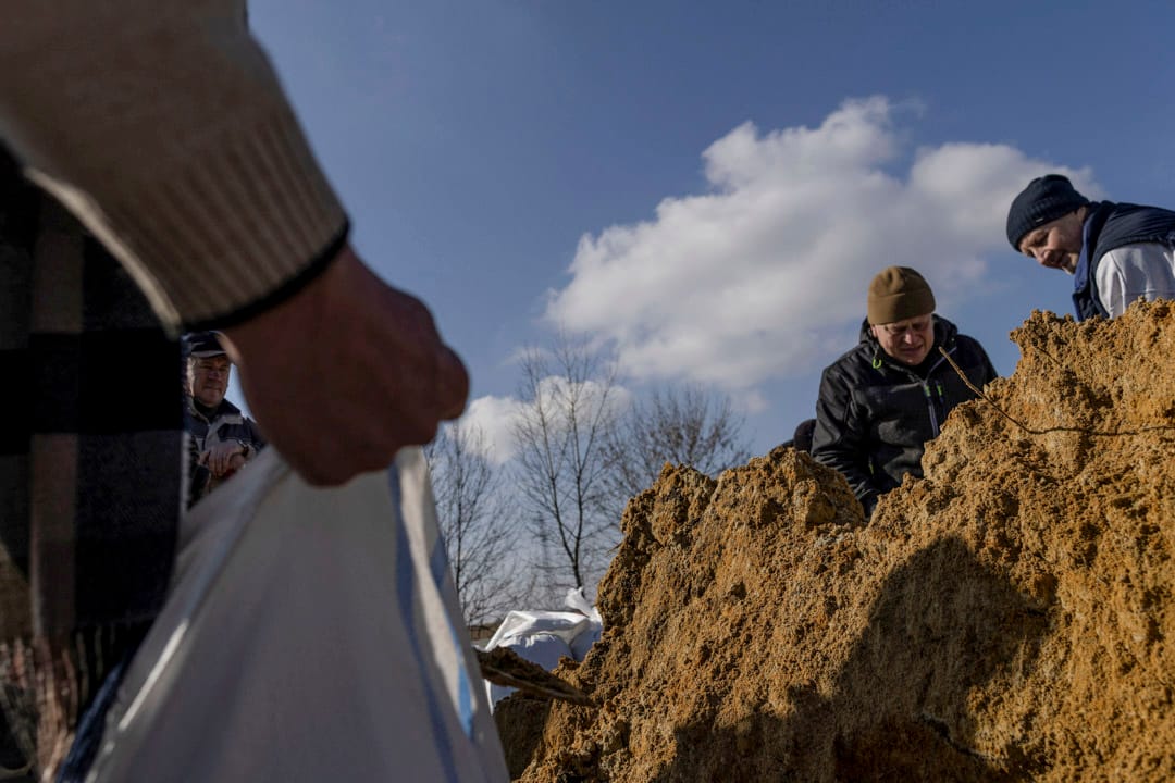 2022年2月25日，乌克兰中部小镇卡米卡安（Kamianka），当地居民制作沙包，在道路上设置检查站。