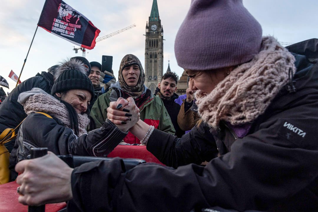 2022年1月30日，加拿大首都渥太華，兩名反疫苗示威者在國會山莊外拗手瓜。