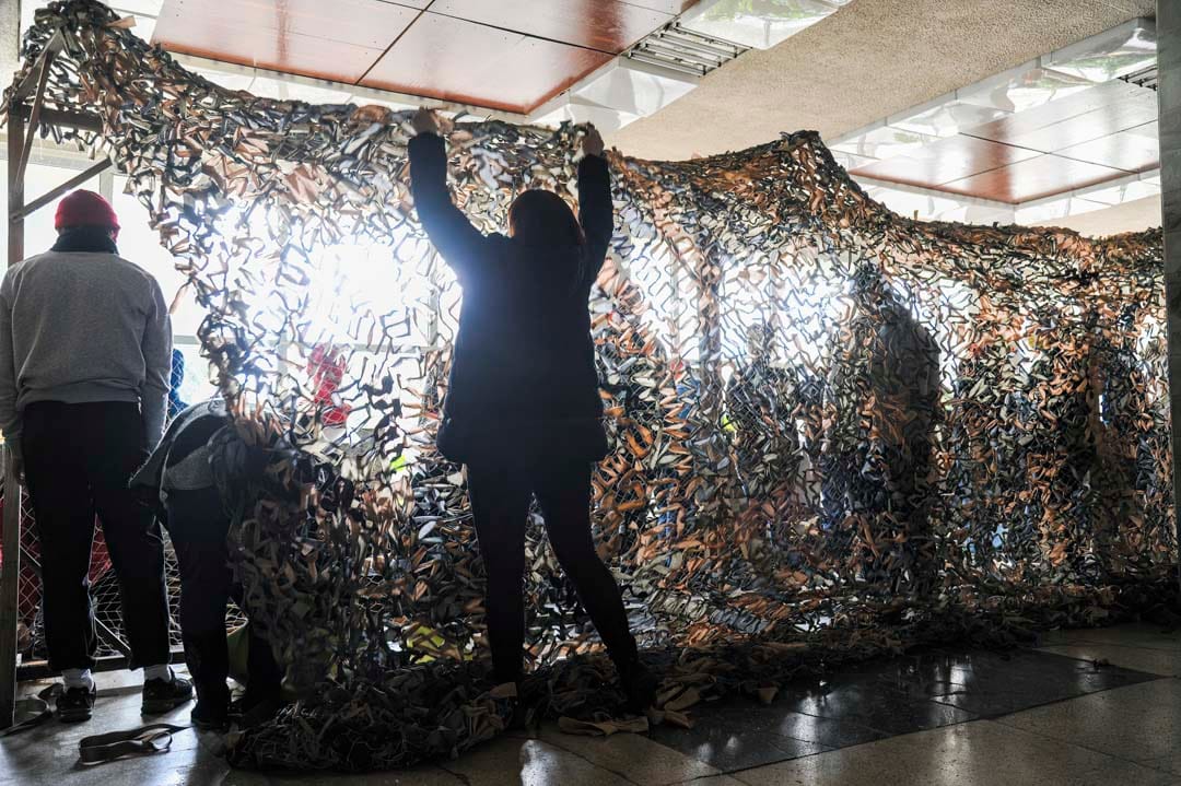 2022年2月24日，乌克兰西部城市利沃夫，义工为乌克兰士兵编织迷彩网。