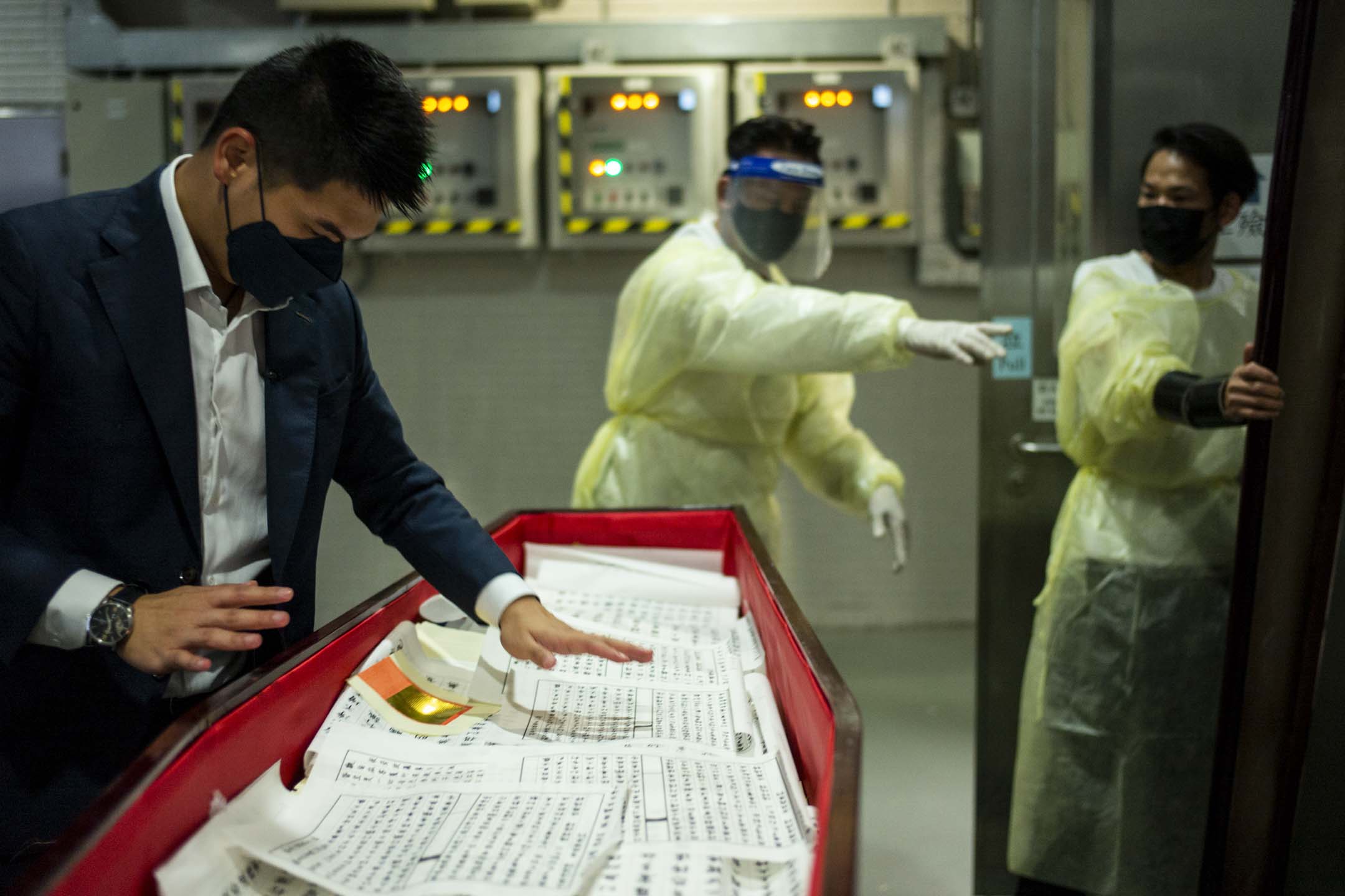 2022年3月17日，一名70歲的長者因感染Covid-19離世，殯葬儀式中，禮儀師在封棺之前把100張由家人親手寫的《心經》，鋪在先人遺體上。攝：林振東/端傳媒     