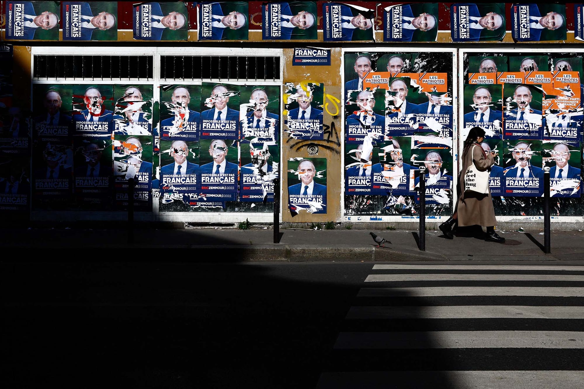2022年4月4日，一名婦女從一堵被撕毀的法國極右翼評論員澤穆爾（Eric Zemmour）的總統競選海報旁走過。