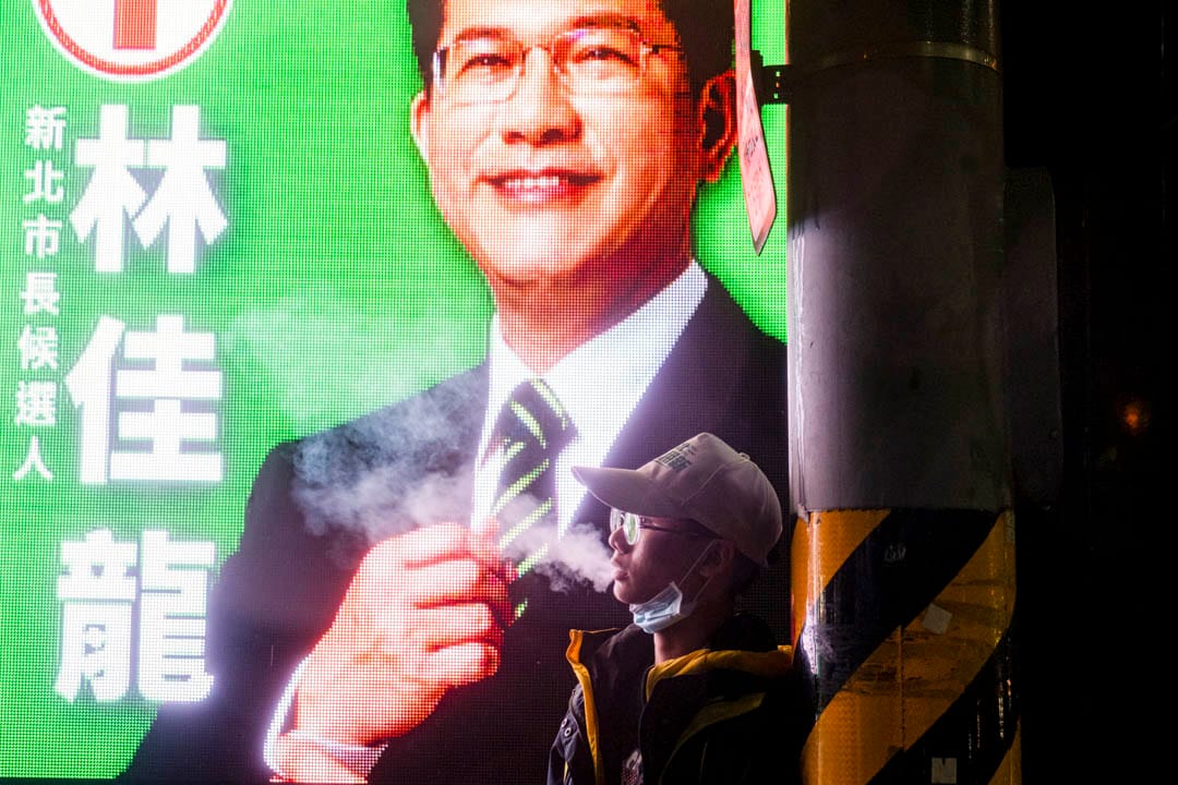 2022年11月24日，民進黨新北市市長候選人林佳龍舉行造勢晚會，一名支持者在旁抽煙。